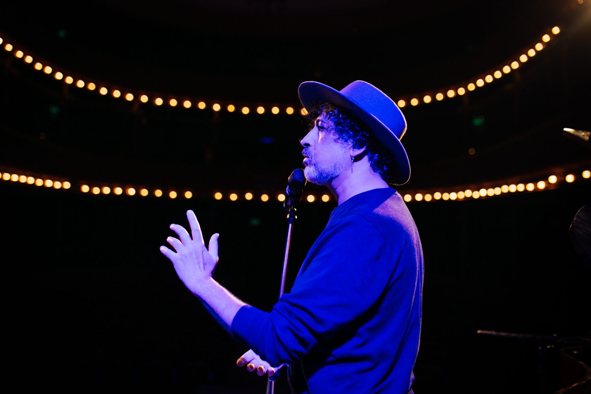 Manuel García en concierto, sombrero azul, micrófono. Celebra 20 años de Pánico.