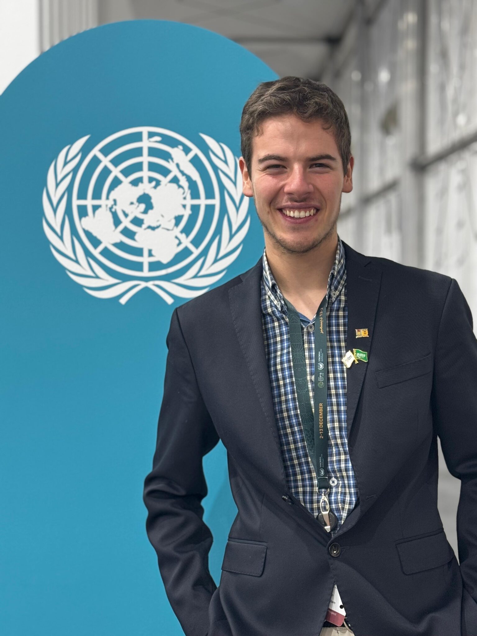 Benjamín Sánchez, estudiante USM, en COP16 Riad, Arabia Saudita. Sonríe ante logo ONU, representando a Chile y Latam.