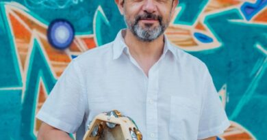 Daniel Muñoz, director de "Cantando a la Vida" y Taller A Viva Voz, con pandero y gorra. Mural vibrante.