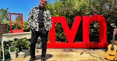 Luis Jara sonríe en un escenario exterior con letras TVN y guitarra. Celebra su regreso a Olmué y 40 años de trayectoria.