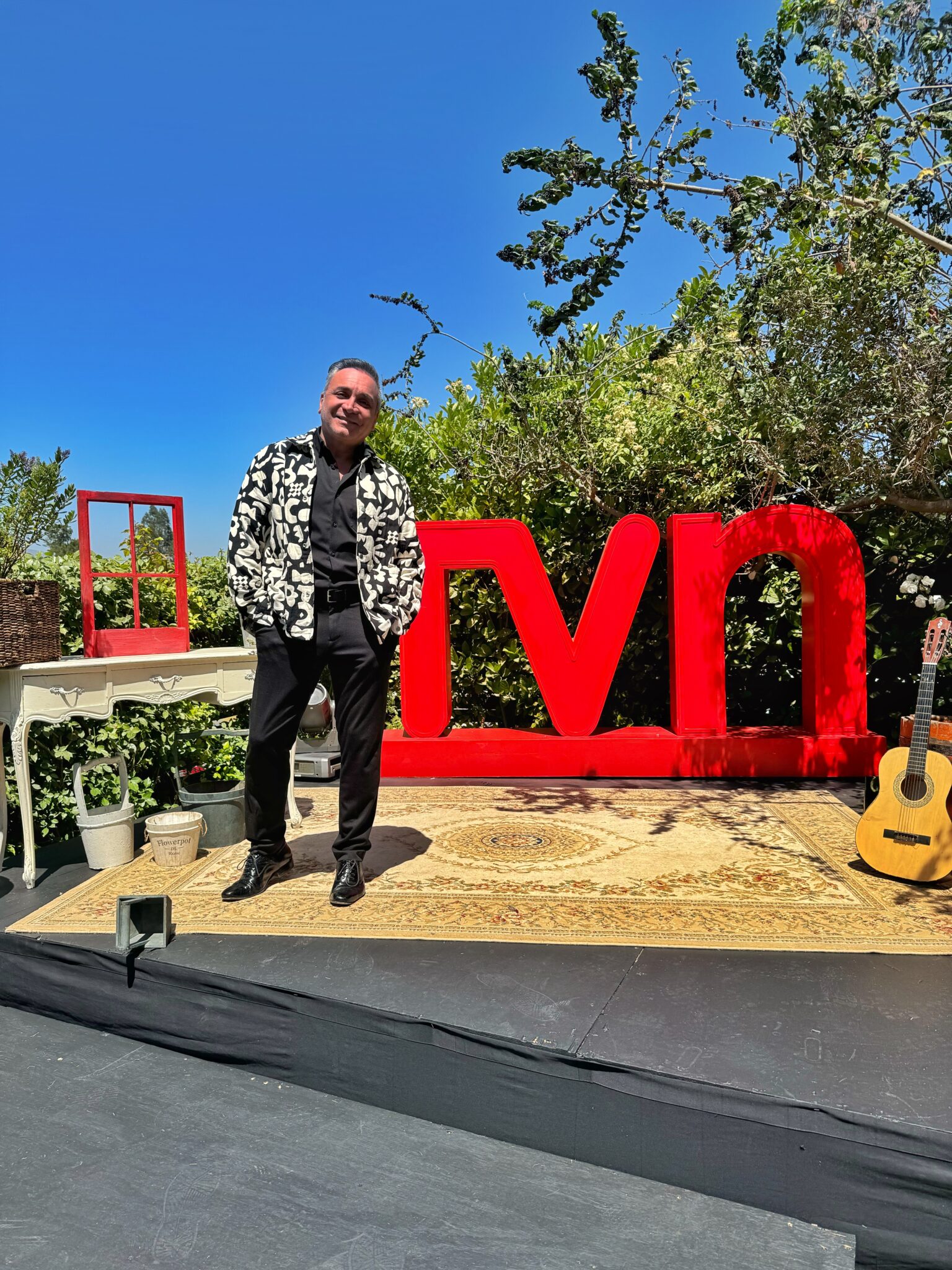 Luis Jara sonríe en un escenario exterior con letras TVN y guitarra. Celebra su regreso a Olmué y 40 años de trayectoria.