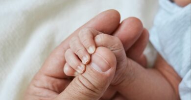 Mano de bebé sujetando dedo adulto. 11 guaguas con "síndrome del hombre lobo" por minoxidil accidental.