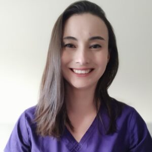 Chris Pefaur, nutricionista Nutrapharm, sonríe. Pelo oscuro, uniforme morado. Teletrabajo y salud.