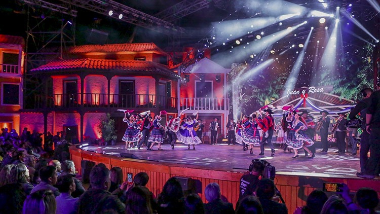 Festival del Huaso de Olmué en El Patagual. Bailarines folclóricos en escenario con casas coloniales iluminadas.