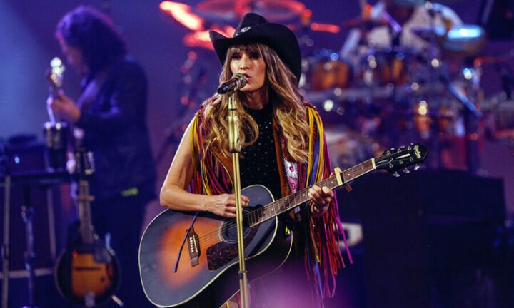 Hanna de Ha-Ash en Viña del Mar. Con sombrero vaquero y flecos, canta y toca guitarra acústica en el escenario.