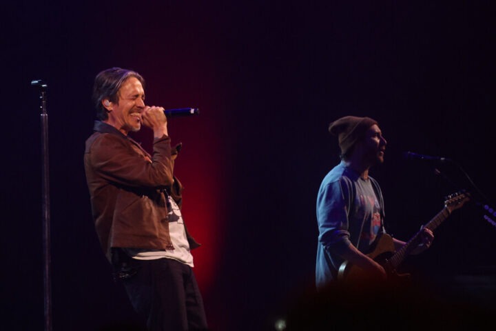 Brandon Boyd de Incubus sonríe cantando en Viña 2025; Mike Einziger toca guitarra en concierto enérgico.