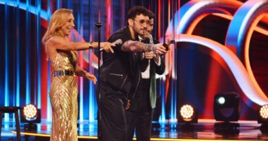 Comediante Edo Caroe sonríe en Viña 25, sosteniendo Gaviotas de Plata y Oro junto a presentadora.