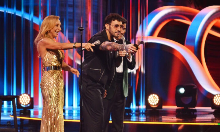 Comediante Edo Caroe sonríe en Viña 25, sosteniendo Gaviotas de Plata y Oro junto a presentadora.
