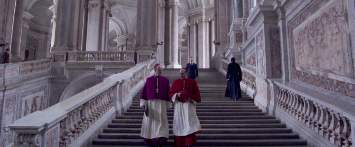Cónclave: Cardenales O'Malley (Brían F. O’Byrne) y Lawrence (Ralph Fiennes) bajan gran escalera del Vaticano.