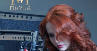 Mayla, artista tropical, grabando su nueva versión de "Mentira". Pelo rojo, micrófono, logo Mayla y título.
