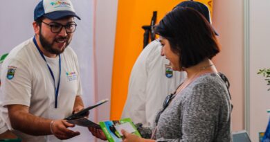 Hombre de Puchuncaví entrega folletos de destinos turísticos a una mujer en la Feria Internacional FITVAL Valparaíso Región.