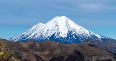 Volcán nevado y laderas áridas en Chile. Impacto del cambio climático: reducción de nieve, aridez y recursos hídricos.