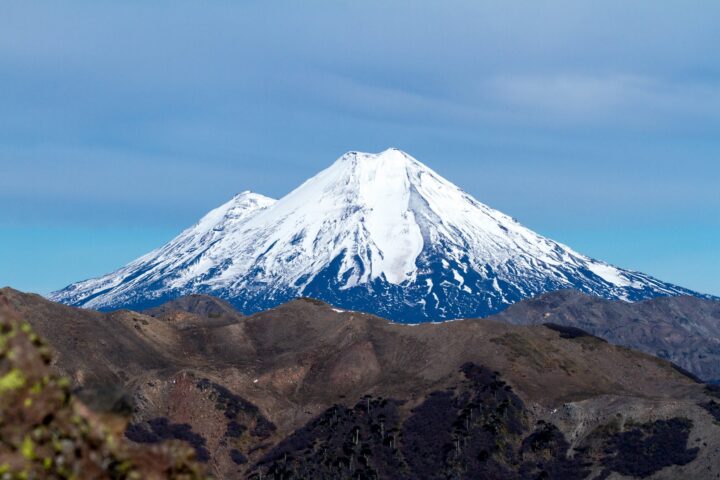 Volcán nevado y laderas áridas en Chile. Impacto del cambio climático: reducción de nieve, aridez y recursos hídricos.