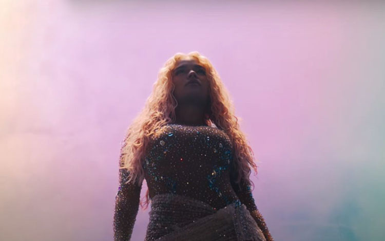 Aquí tienes una opción de texto alternativo: Karol G con cabello rubio ondulado y vestido brillante, mirando al cielo. Documental 'Mañana Fue Muy Bonito' en Netflix. *(111 caracteres)*