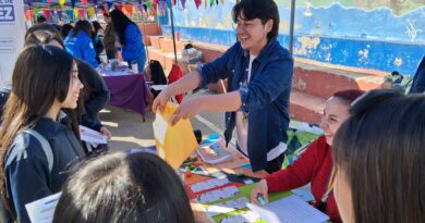 Feria Bienestar, Escuela Chorrillos. Jóvenes reciben Pasaporte de Emociones en stand de salud mental y diversidad, con banderines arcoíris.