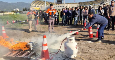 Funcionario de SaludQuillota usa extintor en simulador de fuego. Capacitación práctica en emergencias y seguridad en centros de salud.