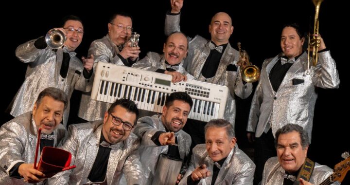 Leo Soto y La Sonora de Todos, músicos de cumbia chilena, posan sonrientes con trompetas, teclado y percusión en trajes plateados.