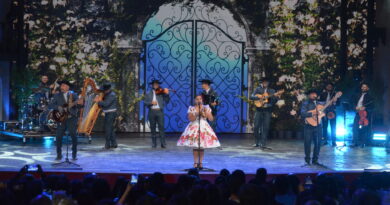 Cantante en vestido floral y banda folclórica en escenario del Festival del Huaso de Olmué. Músicos con arpa, guitarras, violín. Fondo digital floral y portal.