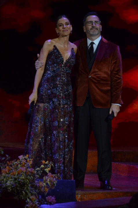 Animadores del Festival del Huaso de Olmué 2026. Ella con vestido de noche brillante; él, traje con blazer de terciopelo. Elegancia en escenario.