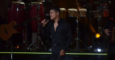 Rey de la Cumbia Chilena canta apasionado en concierto de Olmué. De negro, micrófono en mano, congas y guitarra al fondo.