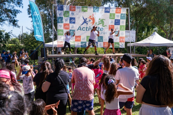 Activate Quilpué: Instructores guían baile en escenario con público activo al aire libre. Evento deportivo comunitario en Quilpué.