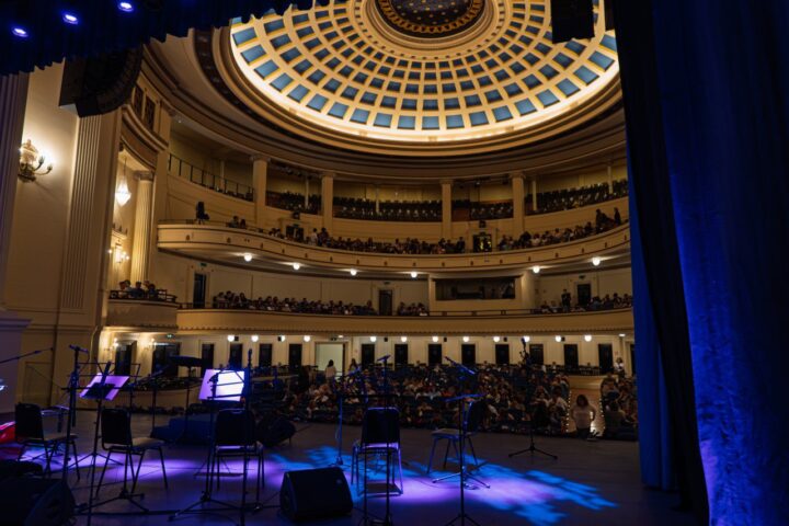 Teatro Municipal Viña del Mar lleno. Escenario iluminado con equipo, público en platea y palcos. Cúpula ornamentada.