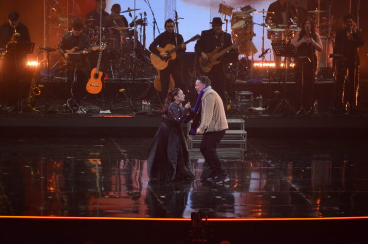 Gloria Estefan y un José Antonio Neme bailan enérgicamente en el escenario de Viña del Mar, acompañados por su banda.