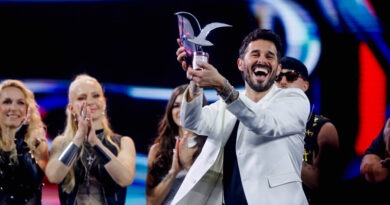 Ganador sonriente levanta Gaviota de Plata. Otros artistas aplauden en el festival.