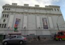 Teatro Municipal Valparaíso con banner de congreso ufológico. Calle urbana con auto y bus. Escenario de expertos en inteligencia no humana.