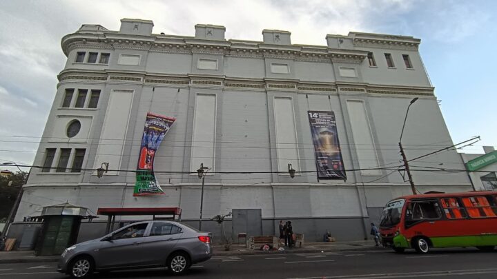 Teatro Municipal Valparaíso con banner de congreso ufológico. Calle urbana con auto y bus. Escenario de expertos en inteligencia no humana.