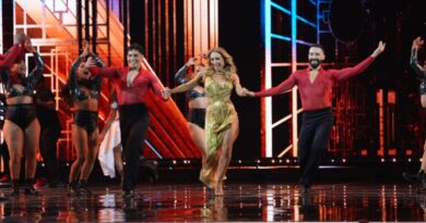 Animadora Karen Doggenweiler bailando alegremente con bailarines al ritmo de "Conga" en el Festival de Viña. Vestido dorado, escenario vibrante.