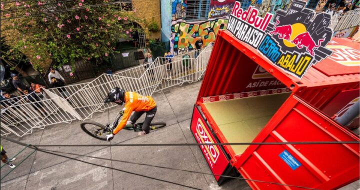 Ciclista de MTB en pleno descenso urbano Red Bull Valparaíso Cerro Abajo, con contenedor rojo y público.