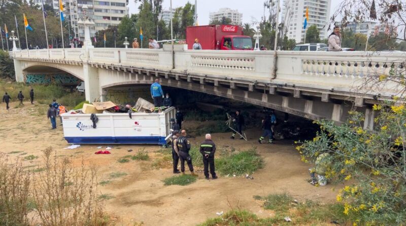 Operativo de limpieza en Estero Marga Marga, Viña del Mar. Equipo municipal retira desechos voluminosos bajo puente. Contenedor rebosante.