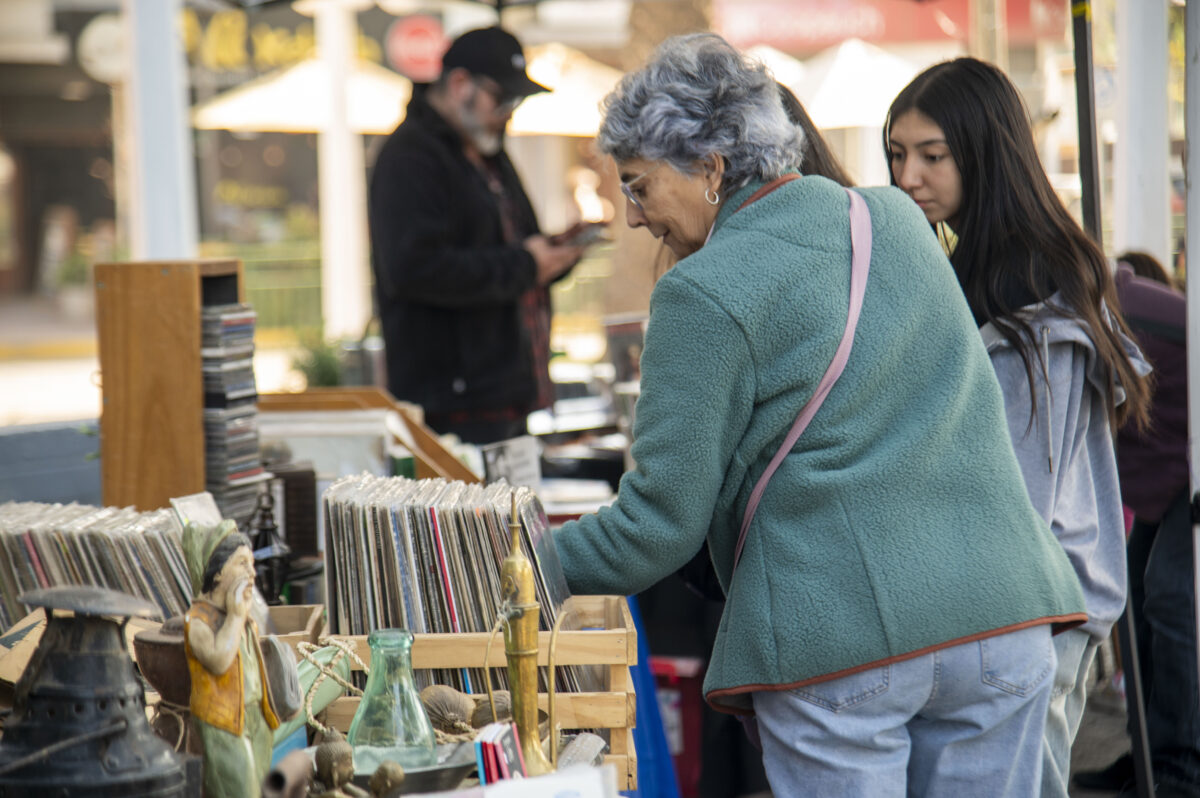 Visitantes explorando objetos y libros en la Feria Patrimonial de Quilpué.