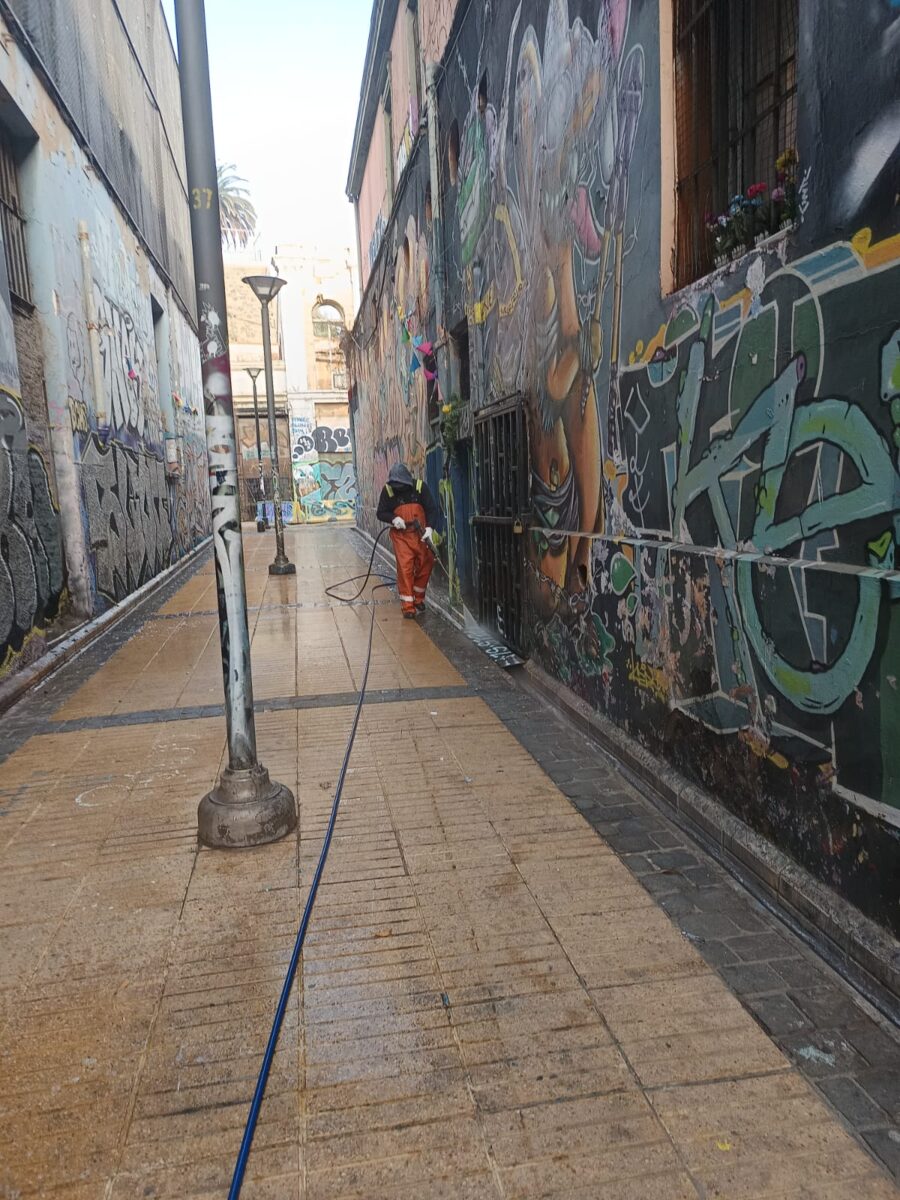 Trabajador municipal limpiando un pasaje con grafitis en Valparaíso.