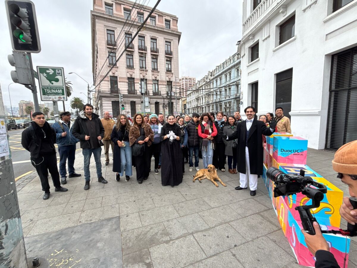 Grupo de personas en una calle de Valparaíso durante el Día del Patrimonio, con el Duoc UC de fondo.