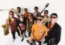 Integrantes de la banda chilena Kelu posando con sus instrumentos musicales sobre un fondo blanco.