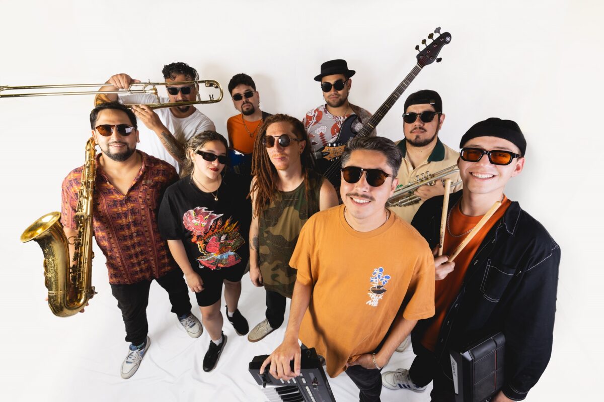 Integrantes de la banda chilena Kelu posando con sus instrumentos musicales sobre un fondo blanco.
