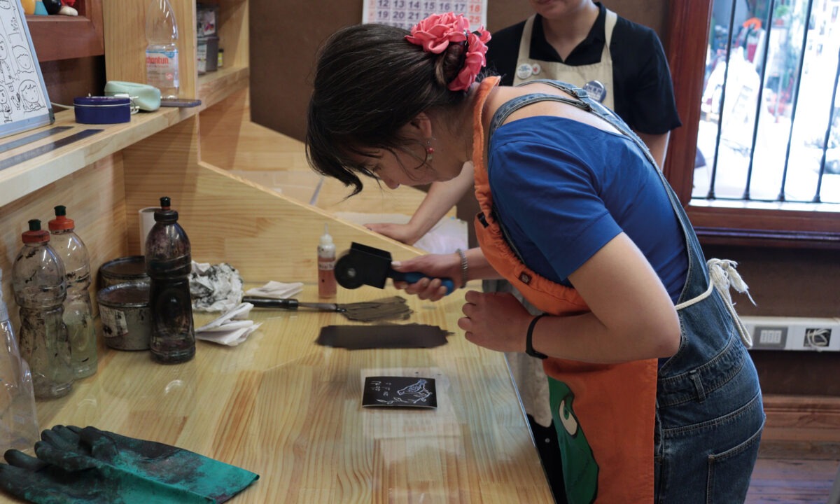 Instructora preparando tinta y rodillo para grabado en el taller del MUG UPLA.