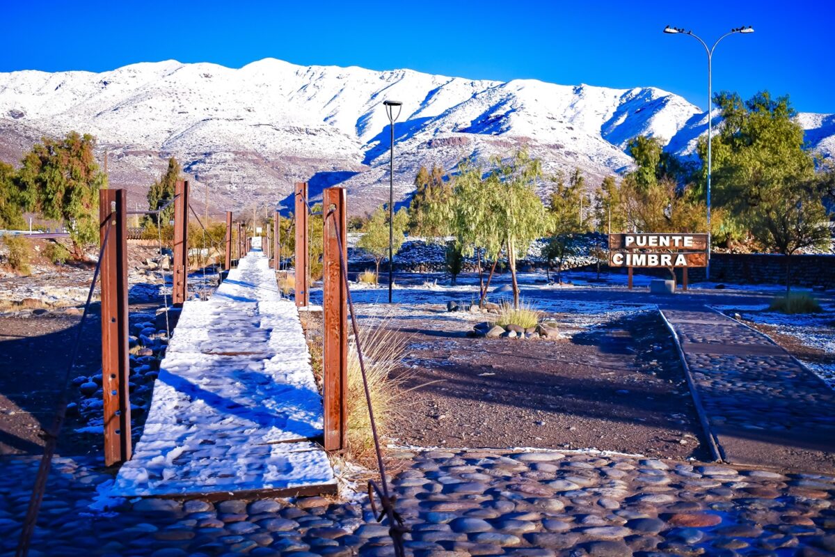 Puente Cimbra en Putaendo nevado con montañas al fondo.