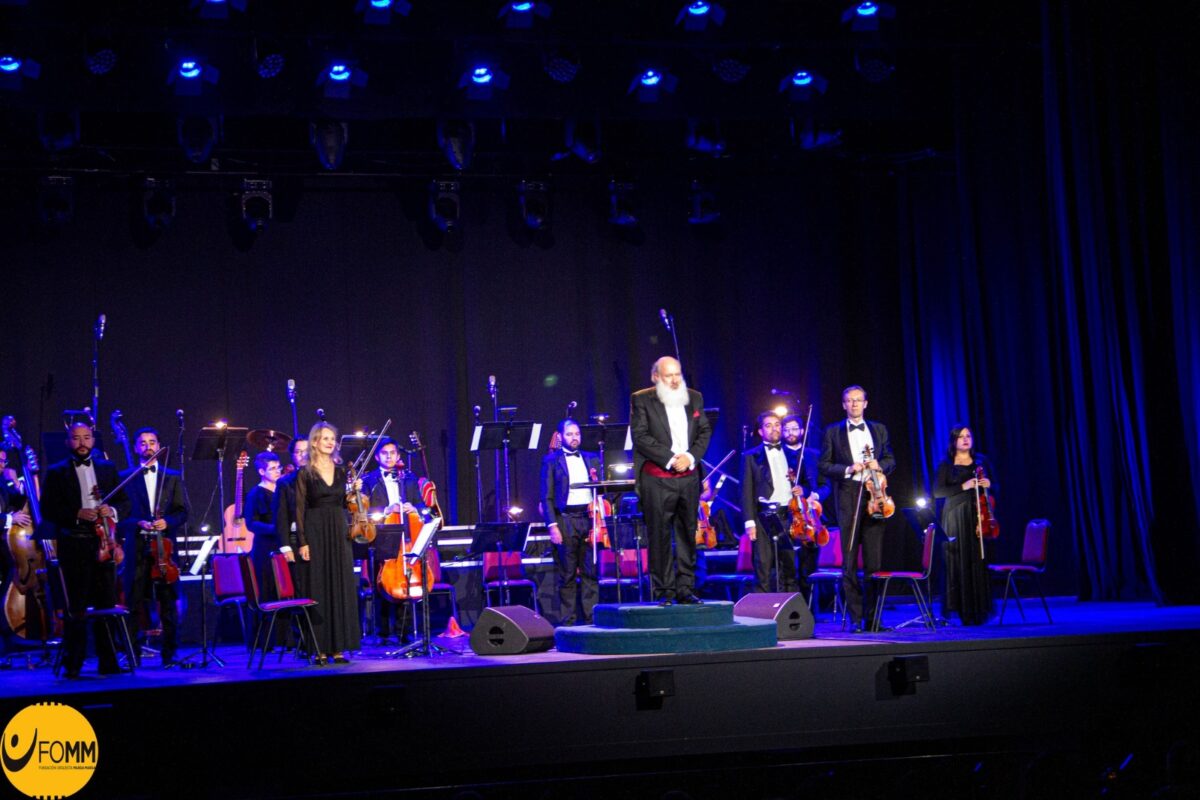 Miembros de la Orquesta Marga Marga y su director saludando al público en el escenario.