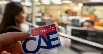 Una persona sosteniendo un sticker con el texto 'tu deuda CAE' en el contexto de una oficina.