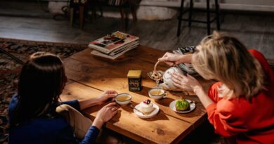 Dos personas compartiendo té y postres en una mesa de madera, simbolizando un momento de pausa y bienestar.