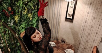 La artista y terapeuta Olivia Mortis posando en un espacio decorado con plantas y estilo clásico.