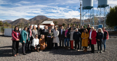 Grupo de personas posando frente a instalaciones de agua y torres de suministro.