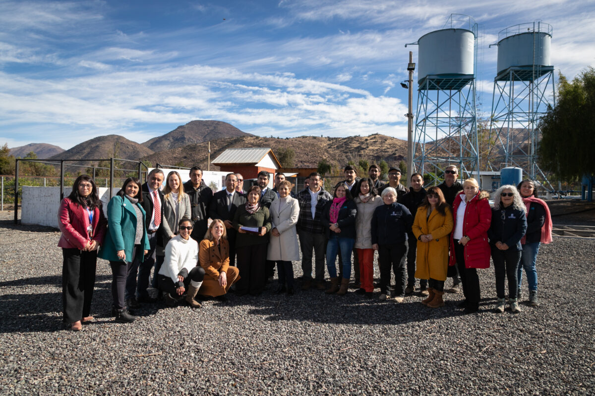 Grupo de personas posando frente a instalaciones de agua y torres de suministro.