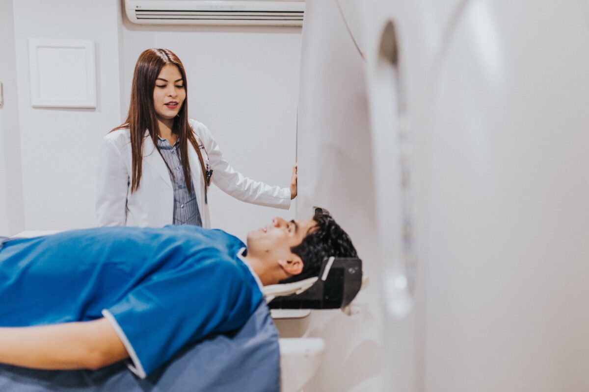 Especialista médica operando equipamiento tecnológico de diagnóstico por imágenes con un paciente.