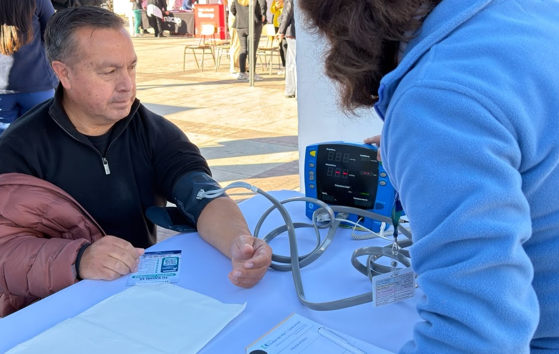 Hombre tomando la presión arterial en un punto de control de salud.