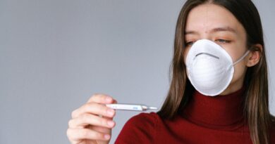 Mujer con mascarilla y termómetro, símbolo de prevención de enfermedades respiratorias.