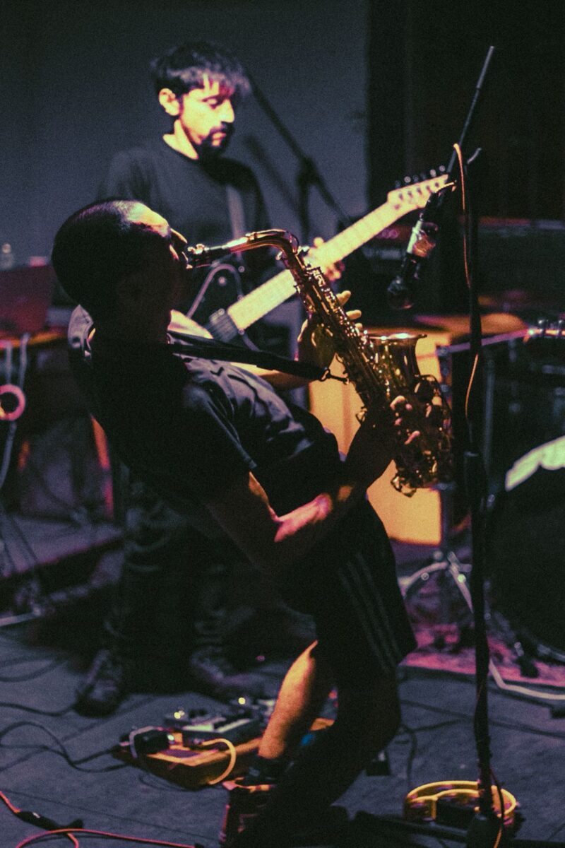 Presentación en vivo de Légamo con saxofonista y guitarrista en escena.